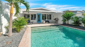 Um imóvel residencial com piscina, um pátio com mobiliário externo e garagem.