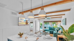 Cozinha moderna com ilha central, luminárias pendentes e vista para a área da piscina.