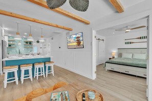 Una cocina moderna con una isla central, taburetes de bar, luces colgantes y un ventanal grande.