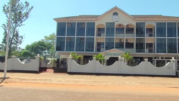 A multi-story building with a prominent entrance, large windows, and a gated driveway. - New Coffee Tree Hotel (Bukoba)