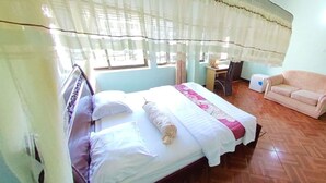 A bedroom with a bed, a chair, a small table, and a sofa. - New Coffee Tree Hotel (Bukoba)