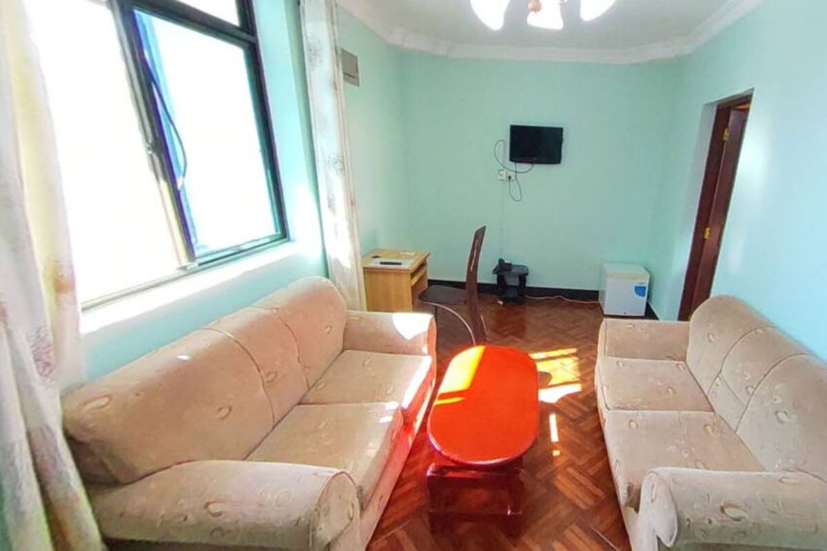 A living room with two beige sofas, a wooden coffee table, and a television on the wall.