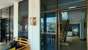 A modern interior with large glass doors leading to a balcony, a wooden bench, and a table with chairs. - New Coffee Tree Hotel (Bukoba)
