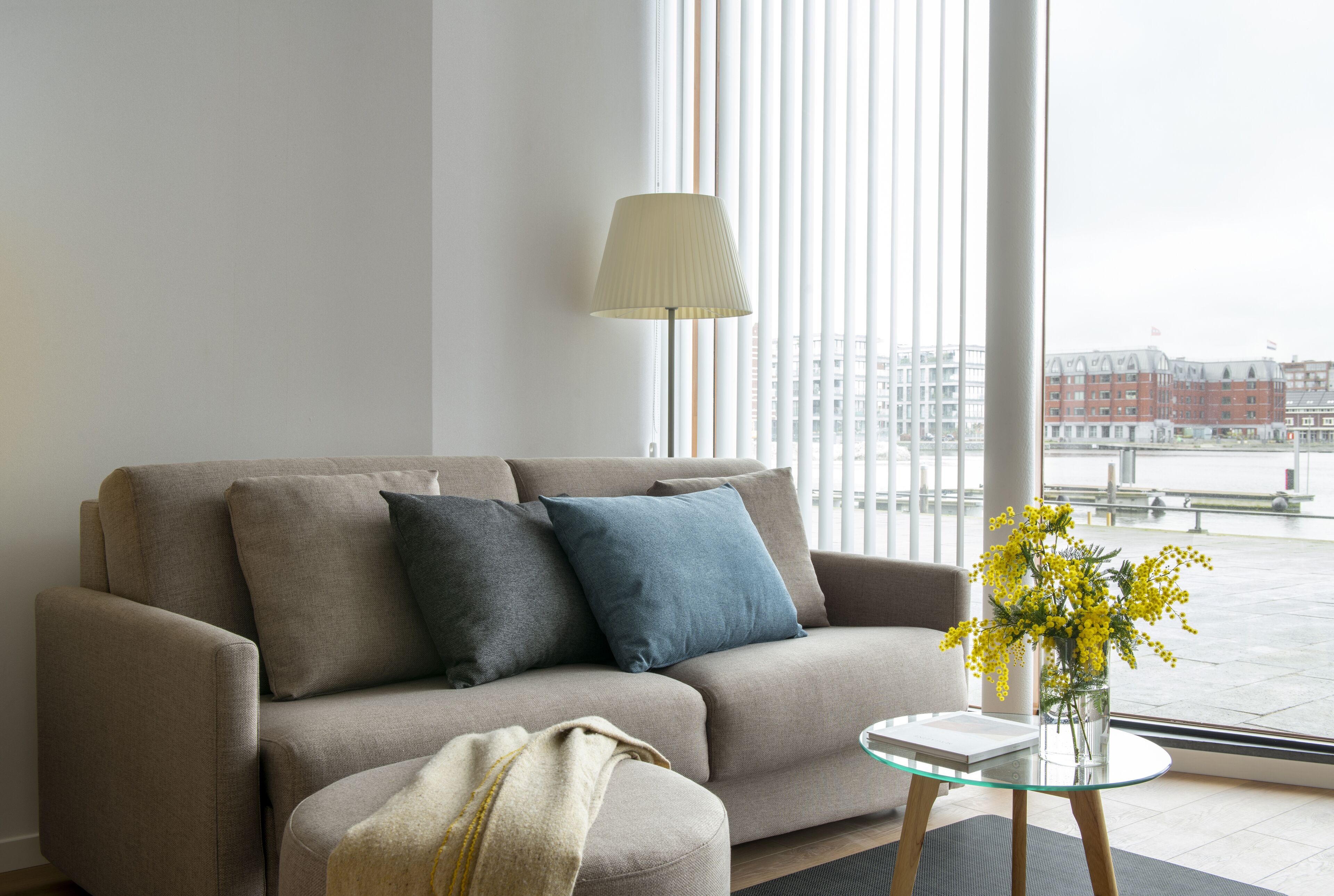 A modern living room with a sofa, a glass coffee table, and a lamp.