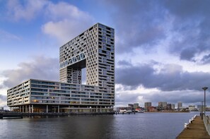 Un hotel moderno de gran altura con un diseño arquitectónico único, que destaca por una sección sobresaliente y múltiples balcones.
