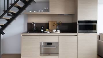 Une cuisine moderne dotée d’appareils électroménagers intégrés, d’un plan de travail en bois et d’un escalier.