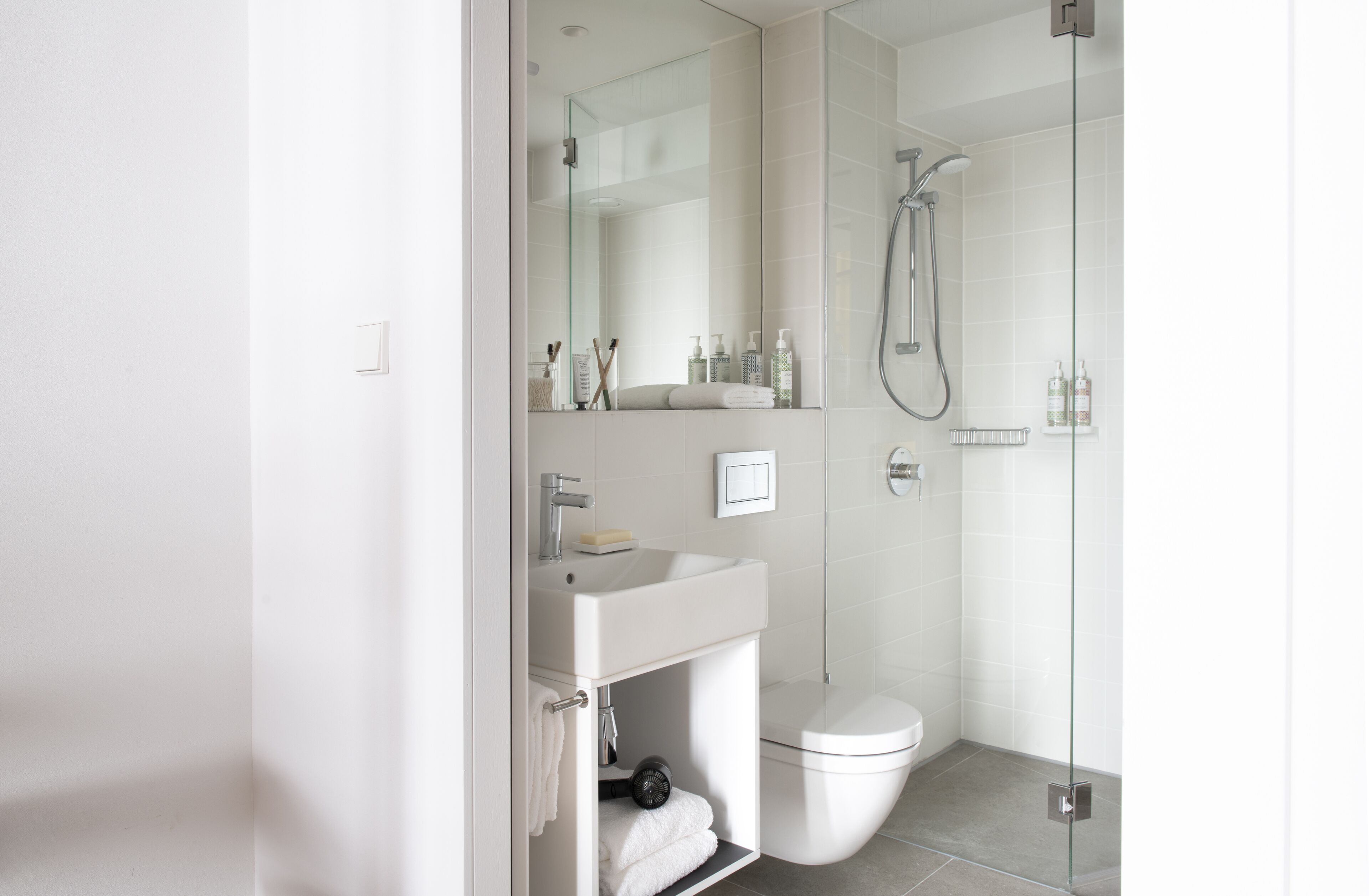 A modern bathroom with a glass-enclosed shower, a white sink, and a toilet.