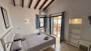 Un dormitorio con cama, mesitas de noche, armario y vistas al exterior.