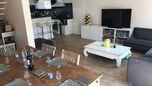 A modern living room with a dining area, a kitchen, and a TV. - Maison AU Calme, Quiet House, 20 Minutes Bordeaux (Gradignan)