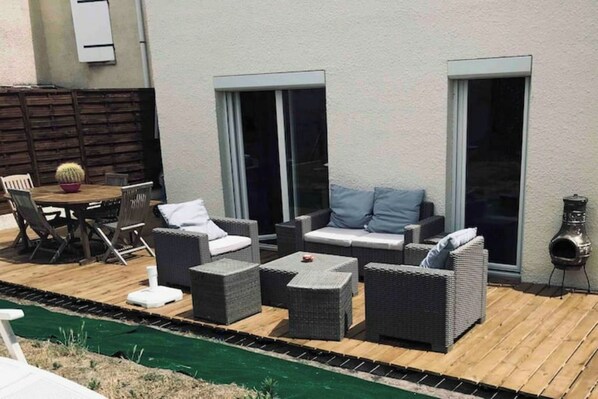 Eine Terrassenanlage im Freien mit Korbmöbeln, einem Tisch und Stühlen.