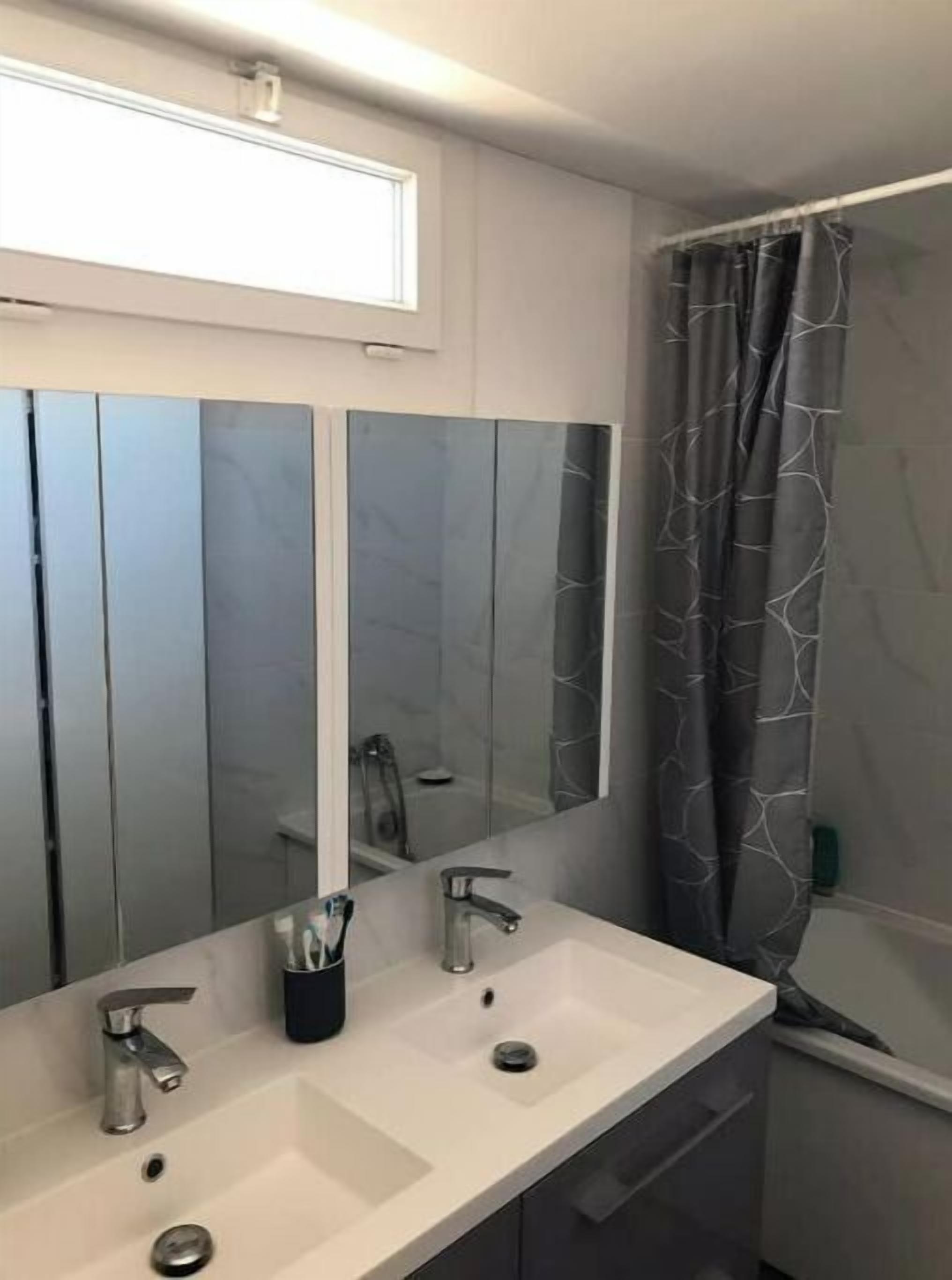 Une salle de bain avec deux lavabos, un grand miroir et un rideau de douche.