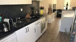 A modern kitchen with white cabinets, a black countertop, and stainless steel appliances. - Maison AU Calme, Quiet House, 20 Minutes Bordeaux (Gradignan)