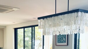 A dining area with a large wooden table, chairs, and a chandelier.