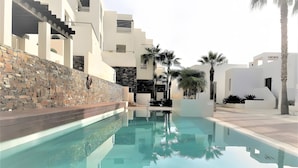 Una piscina amb una paret de pedra i edificis moderns al fons.