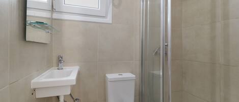 A bathroom with a sink, toilet, and glass shower enclosure.