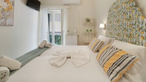 A hotel room with a bed, a television, an air conditioning unit, a balcony door, and a wall-mounted shelf with plants. - M2 Room with Wi-Fi and Air Conditioning (Lefkada)