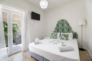A bedroom with a bed, a TV, a balcony with a view, and a lamp.
