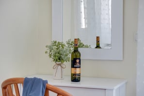 A bottle of wine on a white dresser with a mirror above it and a small plant beside the bottle. - ‘S9 Room’ with Sea View, Wi-Fi and Air Conditioning (Lefkada)