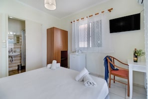 A bedroom with a bed, a wooden wardrobe, a small white desk with a chair, a television, and a window with curtains. - ‘S9 Room’ with Sea View, Wi-Fi and Air Conditioning (Lefkada)