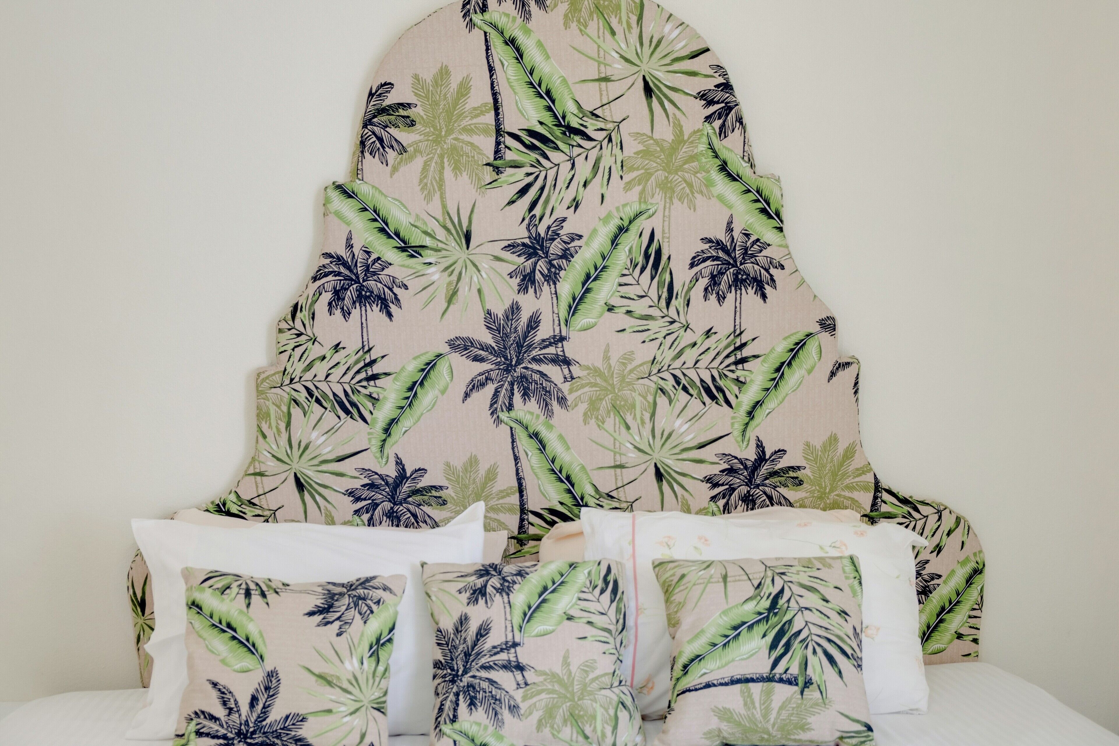 Una cama con cabecera decorada con un diseño de hojas tropicales.