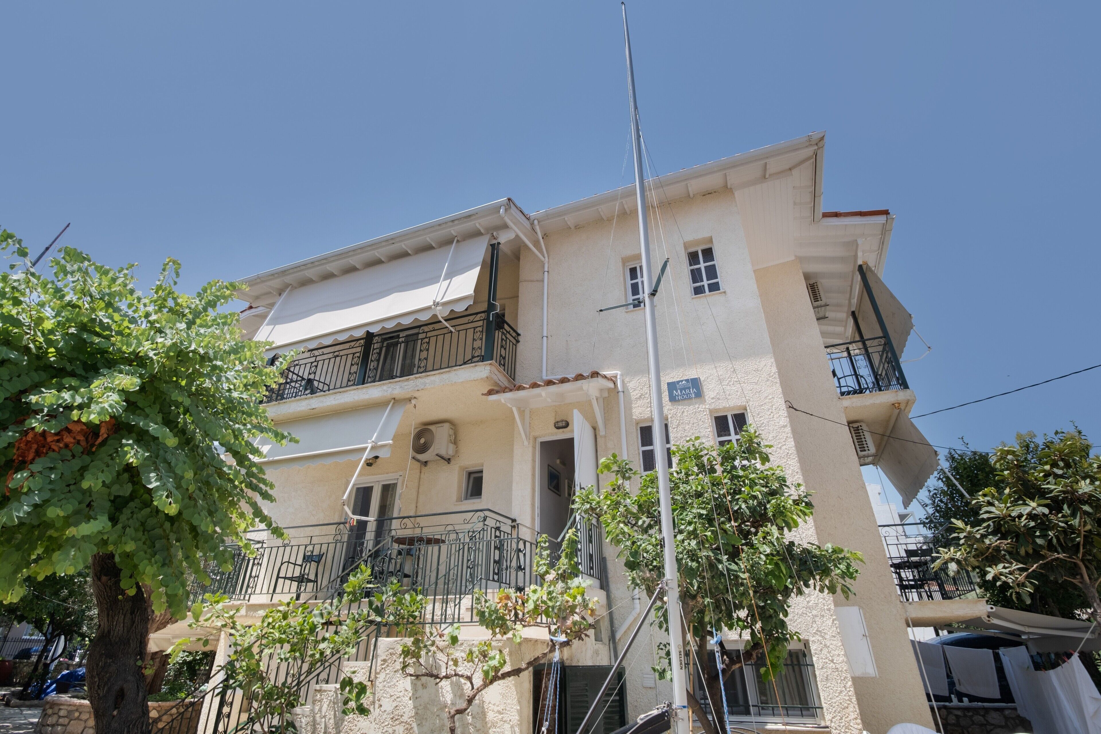 A two-story building with balconies, a flagpole, and a clear blue sky.