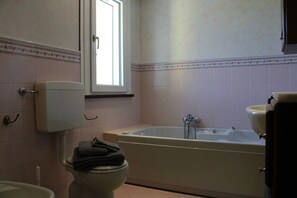 Ein Badezimmer mit Toilette, einer Badewanne und einem Fenster.