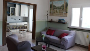 A living room with a sofa, a table with a candle, and a dining area with chairs and a table.