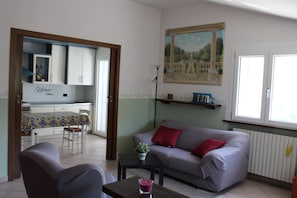 Una sala de estar con un sofá, una mesa con una vela, y un comedor con sillas y una mesa.