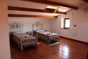 Ein Schlafzimmer mit zwei Metallbetten, Holzbalken, einem Oberlicht und einem kleinen Fenster.