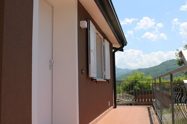 A building with a balcony, a door, and a view of mountains.