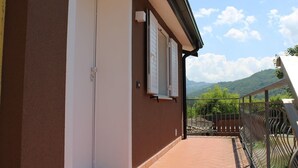 A building with a balcony, a door, and a window with shutters.
