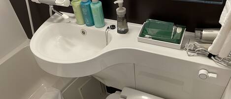 Un baño moderno con un lavamanos blanco, dispensador de jabón y secamanos.