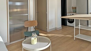 A modern kitchen with a wooden table, a chair, and a round table with a glass jar.