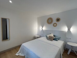 Ein Schlafzimmer mit einem Bett, Nachttischen, einem Spiegel und Wandleuchten.