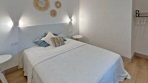 A bedroom with a bed, bedside tables, and wall-mounted lights.