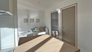 A bedroom with a bed, a bedside table, a wardrobe, and a wall with three framed pictures.