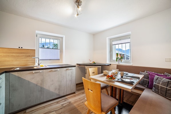Una cocina moderna con comedor, suelo de madera y vistas a las montañas a través de las ventanas.