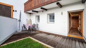 A covered patio with a table and chairs, a wooden ceiling, and a door leading inside. - Apartment "Unterortsgut" with Private Garden & Wi-Fi (Dorf Tirol)