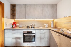 Una cocina moderna con electrodomésticos de acero inoxidable, armarios de madera y un horno empotrado.