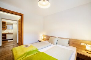 Habitación de hotel con cama, mesitas de noche, un cabecero de madera, espejo y puerta que da a un baño.