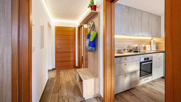 A modern kitchen with wooden cabinets, a built-in oven, and a countertop with various appliances. - Apartment "Unterortsgut" with Private Garden & Wi-Fi (Dorf Tirol)