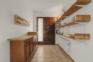 Un couloir étroit avec des meubles en bois, un sol carrelé et des murs blancs.
