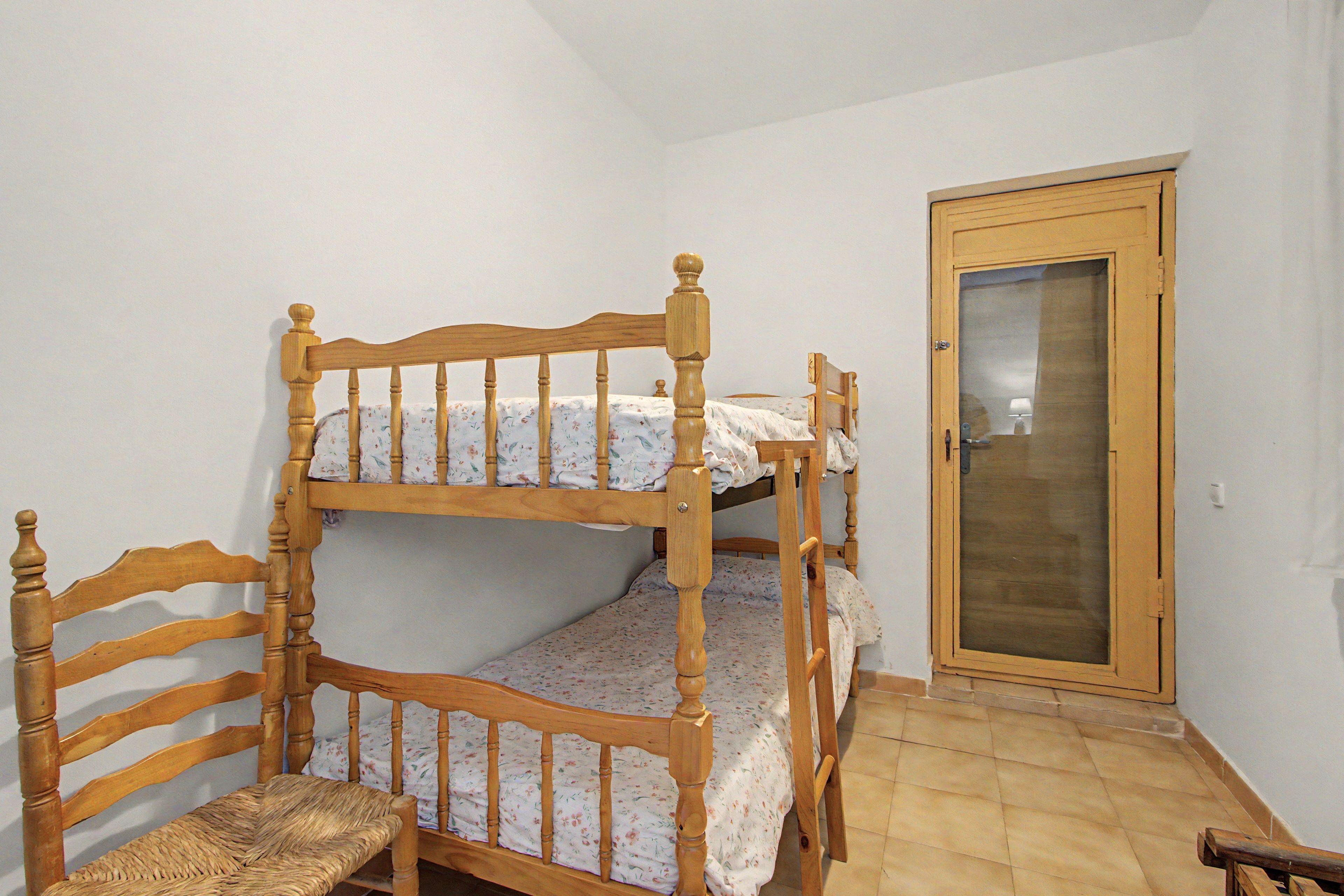 Een kamer met een stapelbed, een houten stoel en een deur.