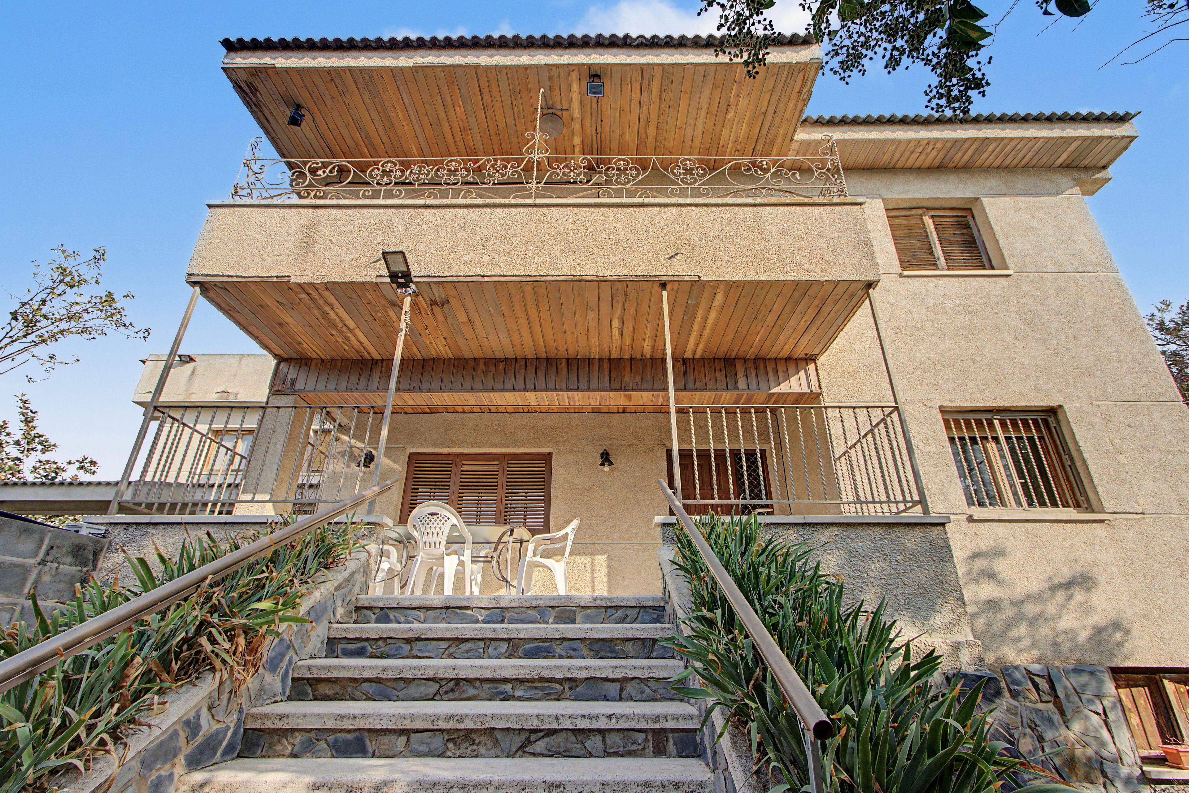Un bâtiment à deux étages avec un escalier en pierre menant à un porche en bois.