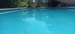 A clear blue pool with tiled edges, surrounded by trees and a lounge area with chairs. - Rural House 'Marina' with Private Terrace, Private Garden and Wi-Fi (Lleida)