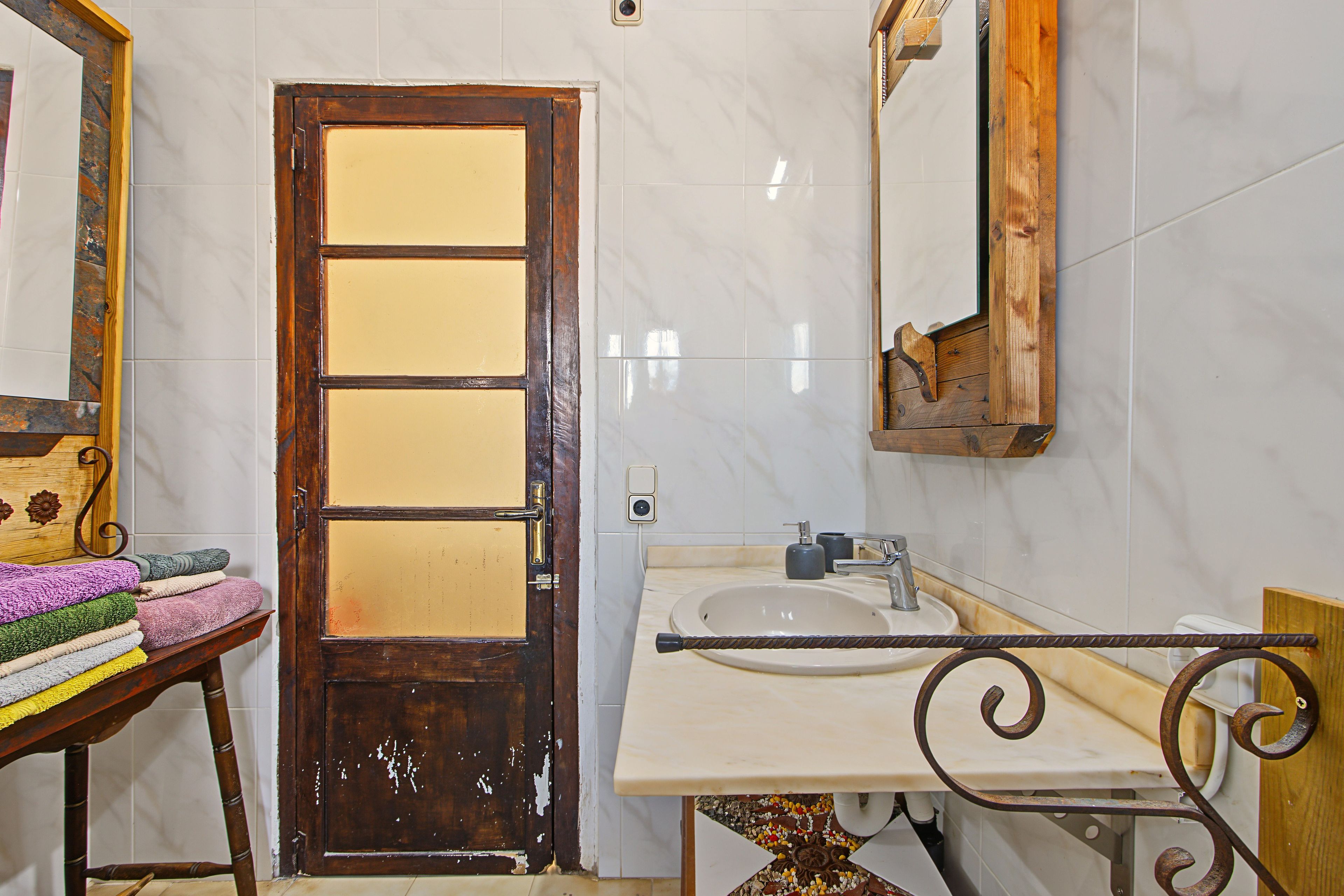 Un baño con puerta de madera, un lavabo y un espejo.