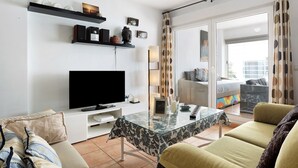 Un saló modern amb un televisor de pantalla plana, una taula de cafè de vidre i seients confortables.