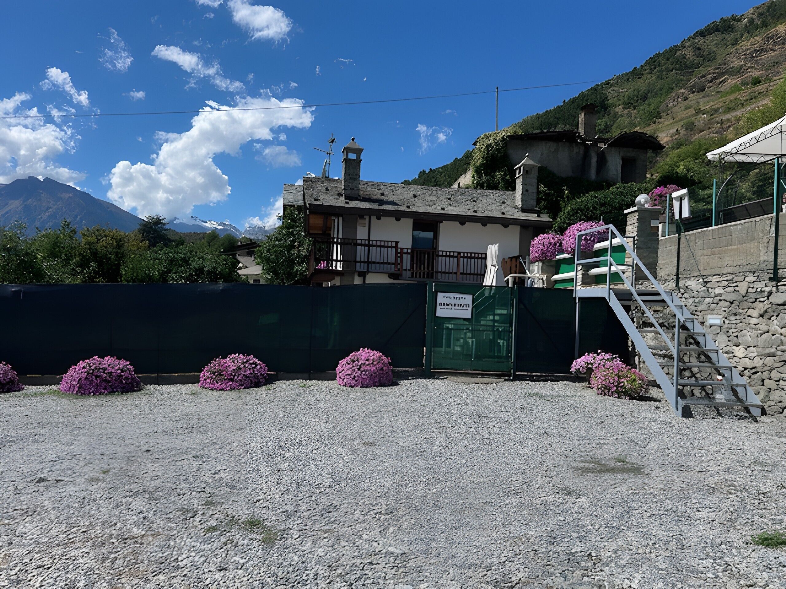 Un bâtiment doté d’une façade en pierre, d’un balcon et d’un escalier menant à une zone abritée.