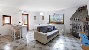 A modern living room with a sofa, a small dining table, and a kitchen area with a built-in stove.