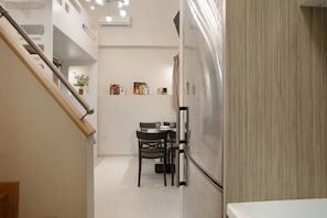 Une cuisine moderne dotée d’un réfrigérateur encastré, d’un escalier en bois et d’un coin repas avec des chaises et une table.